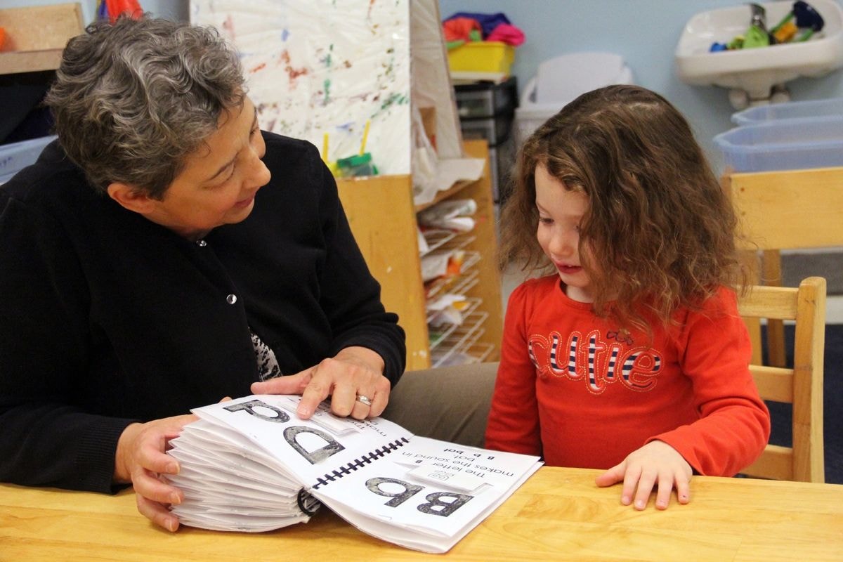 Adult and child reviewing a workbook together in a classroom